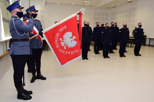 Nowo przyjęci policjanci podczas ślubowania.  Po lewej poczet sztandarowy.