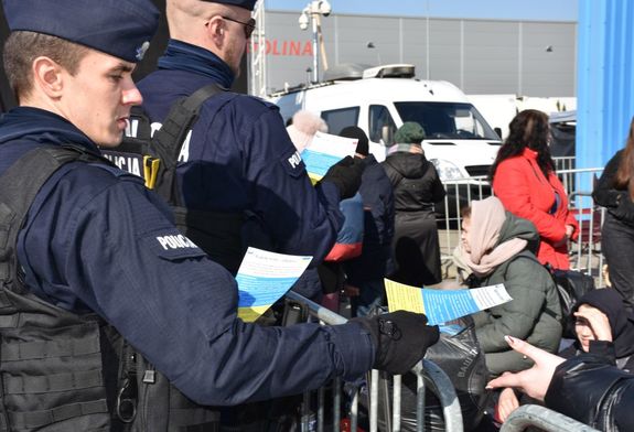 Policjanci rozdają uchodźcom ulotki