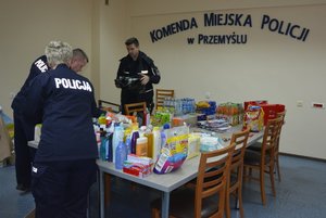 Zdjęcie kolorowe wykonane w porze dziennej -przedstawia pokój Komendy Miejskiej Policji w Przemyślu w którym są  składowane dary dla uchodźców z Ukrainy.