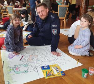 Policjanci biorący udział w spotkaniu wielkanocnym w Polańczyku z rodzinami Ukraińskimi. Na zdjęciach widoczni są policjanci, ksiądz oraz matki z dziecmi