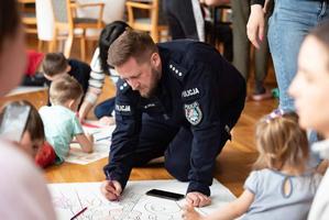 Policjanci biorący udział w spotkaniu wielkanocnym w Polańczyku z rodzinami Ukraińskimi. Na zdjęciach widoczni są policjanci, ksiądz oraz matki z dziecmi