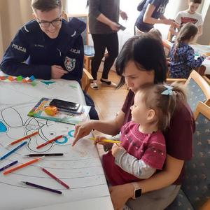 Policjanci biorący udział w spotkaniu wielkanocnym w Polańczyku z rodzinami Ukraińskimi. Na zdjęciach widoczni są policjanci, ksiądz oraz matki z dziecmi