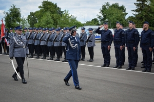 W środku po lewej policjant z szablą, na pierwszym planie Wojewódzki Policji w Rzeszowie, w tle kompania honorowa KWP i nowo przyjęci policjanci.