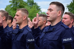 Nowo przyjęci policjanci składają ślubowanie (uniesiona prawa ręka, złożone dwa palce).