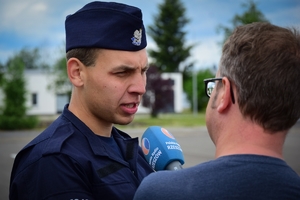 Po lewej nowo przyjęty policjant podczas rozmowy z Radiem Rzeszów (napis na mikrofonie), po prawej reporter radiowy.