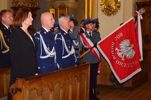 Komendant Główny Policji i Komendant Wojewódzki Policji w Rzeszowie stoją w ławkach w kościele. Obok zaproszeni goście. W tle policyjny sztandar.