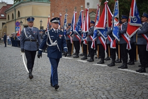 W centrum kadru Komendant Główny Policji idący (widok od przodu) za nim idzie dowódca uroczystości. Po prawej i w tle policyjne sztandary.