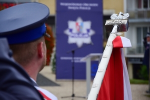 Na pierwszym planie drzewce sztandaru po lewej policjant trzymający sztandar.