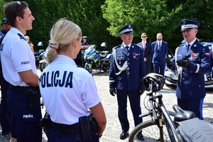 Komendant Główny Policji wraz z Komendantem Wojewódzkim Policji w Rzeszowie odwiedzają piknik policyjny w Białym Ogrodzie. Na zdjęciu komendanci wraz z policjantami pełniącymi służbę na rowerach.