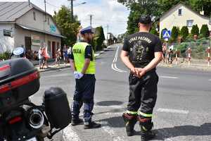 Policjant (po lewej) i strażak (po prawej) stojący przy zakręcie.