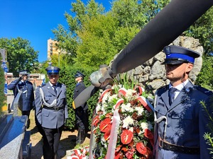 grób st.post. PP Antoniego Krupy, przy grobie stoi policjant odwzorowujący umundurowanie policjanta Policji Państwowej oraz policjant w obecnym umundurowaniu galowym