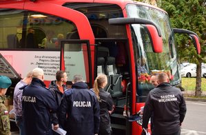 policjanci oraz inni funkcjonariusze stojący przed autobusem do poboru krwi