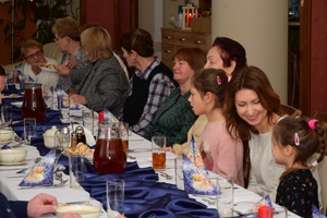 Policjanci podczas spotkania z rodzinami poległych policjantów. Uczestnicy spotkania dzielą się opłatkiem i składają sobie życzenia przy wigilijnym stole.