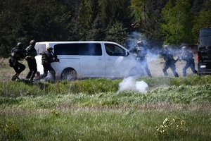 Policyjni antyterroryści i amerykańscy żołnierze podczas wspólnych ćwiczeń, na terenie zielonym.