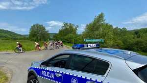 zdjęcia przedstawiają uczestników- kolarzy podczas przejazdów w wyścigu &quot; Orlen Lang Team Race. Kolarze w trakcie przejazdu, na pierwszym planie stoi oznakowany radiowóz policyjny.