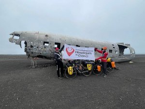 wrak samolotu obok którego stoją mężczyźni z rozwieszoną flagą