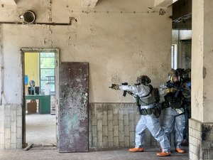 umundurowani policyjni kontrterroryści  w szyku bojowym, z bronią wchodzą do budynku
