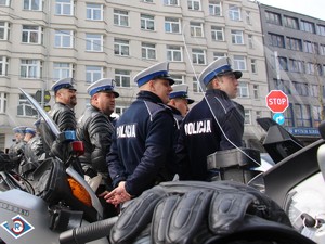 profil sześciu policjantów z ruchu drogowego  w białych czapkach - zdjęcie zrobione zza motocykli