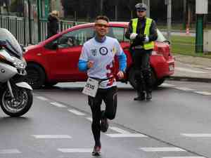 biegacz na trasie maratonu w tle policjant kierujacy ruchem