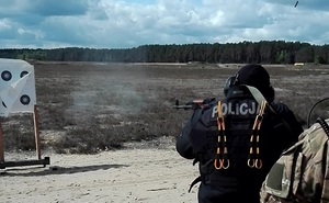 Policjant strzela do tarczy z broni długiej