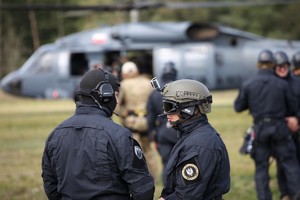 Policyjni zamaskowani kontrterroryści i Black Hawk w tle.