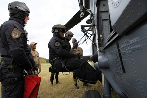 Policyjni kontrterroryści ćwiczą schodzenie po linie z helikoptera stojącego na ziemi