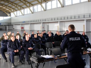 Policjant ze sztabu podczas szkolenia, w tle policjanci uczestnicy szkolenia