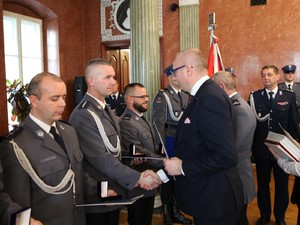 wojewoda wręcza gratulacje policjantowi