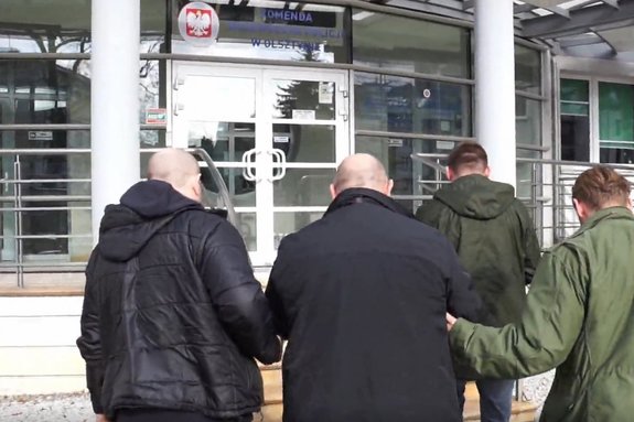 Zatrzymany mężczyzna prowadzony przez policjantów