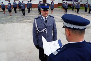 Policjant odbierający akt mianowania od nadinsp. Tomasza Klimka