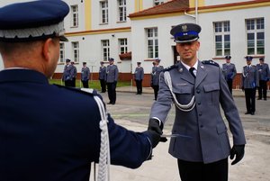 Policjant odbierający akt mianowania od nadinsp. Tomasza Klimka