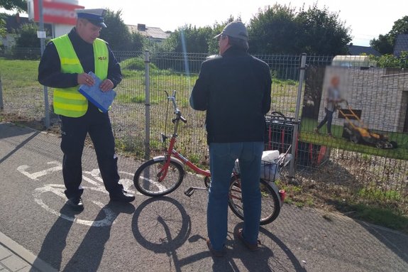 Policjant podczas kontroli drogowej rowerzysty. Rowerzysta, rower i policjant na ścieżce rowerowej