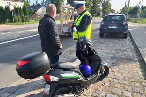 Policjant podczas kontroli drogowej motorowerzysty. Policjant, skuter i kierujący przy drodze.