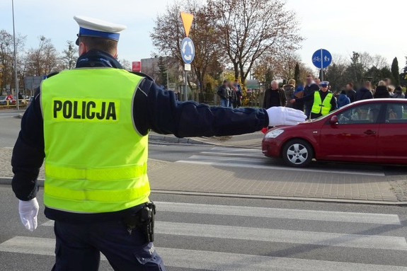 Policjant kierujący ruchem przy przejściu dla pieszych obok cmentarza