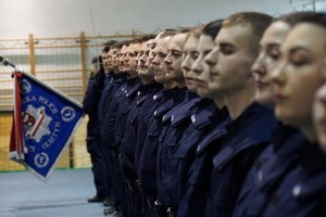 Policjanci stojący w szeregu i sztandar KWP w Olsztynie w tle