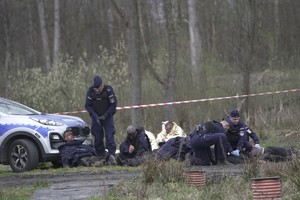 Ranni leżący przy radiowozie i policjanci udzielający im pomocy