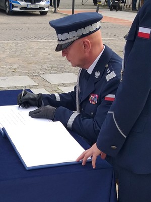 Komendant Główny Policji składa podpis w księdze pamiątkowej