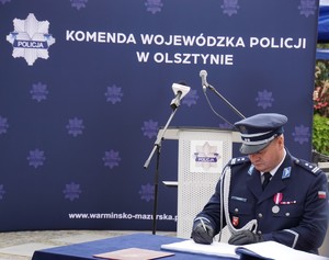 Komendant Powiatowy Policji w Nidzicy składa podpis w księdze pamiątkowej
