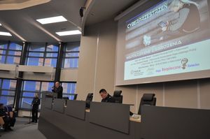 Na zdjęciu osoba w garniturze wygłasza referat.
