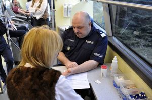 Na zdjęciu widoczni mężczyzna i kobieta.Mężczyzna w policyjnym mundurze Komendant Wojewódzki Policji w Katowicach nadinsp. Krzysztof Justyński w trakcie oddawania krwi.