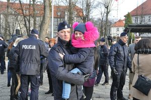 zdjęcie przedstawia nowo przyjętego policjanta z dzieckiem na rękach