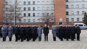 Zdjęcie przedstawia Ministra Spraw Wewnętrznych i Administracji Joachima Brudzińskiego, który pozuje do zdjęcia z Komendantem Głównym Policji gen. insp. Jarosławem Szymczykiem i ślubującymi policjantami.