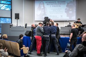 Policjanci i motocykliści wnoszą na scenę wokalistę na wózku inwalidzkim
