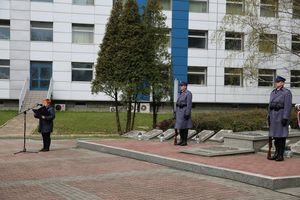 Fotografia kolorowa. Na zdjęciu widoczni policjanci stojący przed grobem.