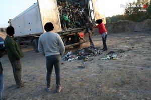 Zdjęcie przedstawia samochód ciężarowy wysypujący odpady oraz 3 osoby stojące obok pojazdu