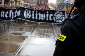 na zdjęciu widoczne ramię i pagon policjanta, w tle zbliżający się kibice gliwickiej drużyny