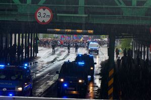 na zdjęciu oznakowane radiowozy oraz policjanci zabezpieczający przemarsz kibiców