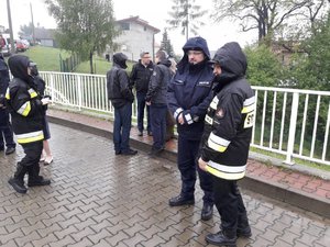 Zdjęcie przedstawia strażaków stojących obok Komendanta Wojewódzkiego Policji w Katowicach nadinsp. Krzysztofa Justyńskiego przy zaporze w Wilkowicach, w tle obecny jest Wojewoda Śląski Jarosław Wieczorek rozmawiający z innymi osobami