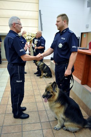 Zastępca Komendanta Wojewódzkiego Policji w Katowicach mł. insp. Mariusz Krzystyniak gratuluje zwycięzcy tegorocznego wojewódzkiego finału XIX Kynologicznych Mistrzostw Policji w garnizonie śląskim st. asp. Łukaszowi Brzezińskiemu z Komendy Miejskiej Policji w Katowicach z psem Euforia do wyszukiwania zapachów narkotyków