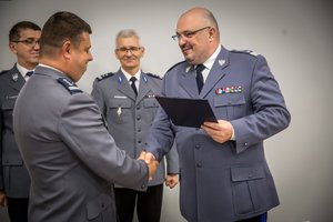 Komendant Wojewódzki Policji w Katowicach nadinsp. Krzysztof Justyński wręcza insp. Piotrowi Kuci adres okolicznościowy